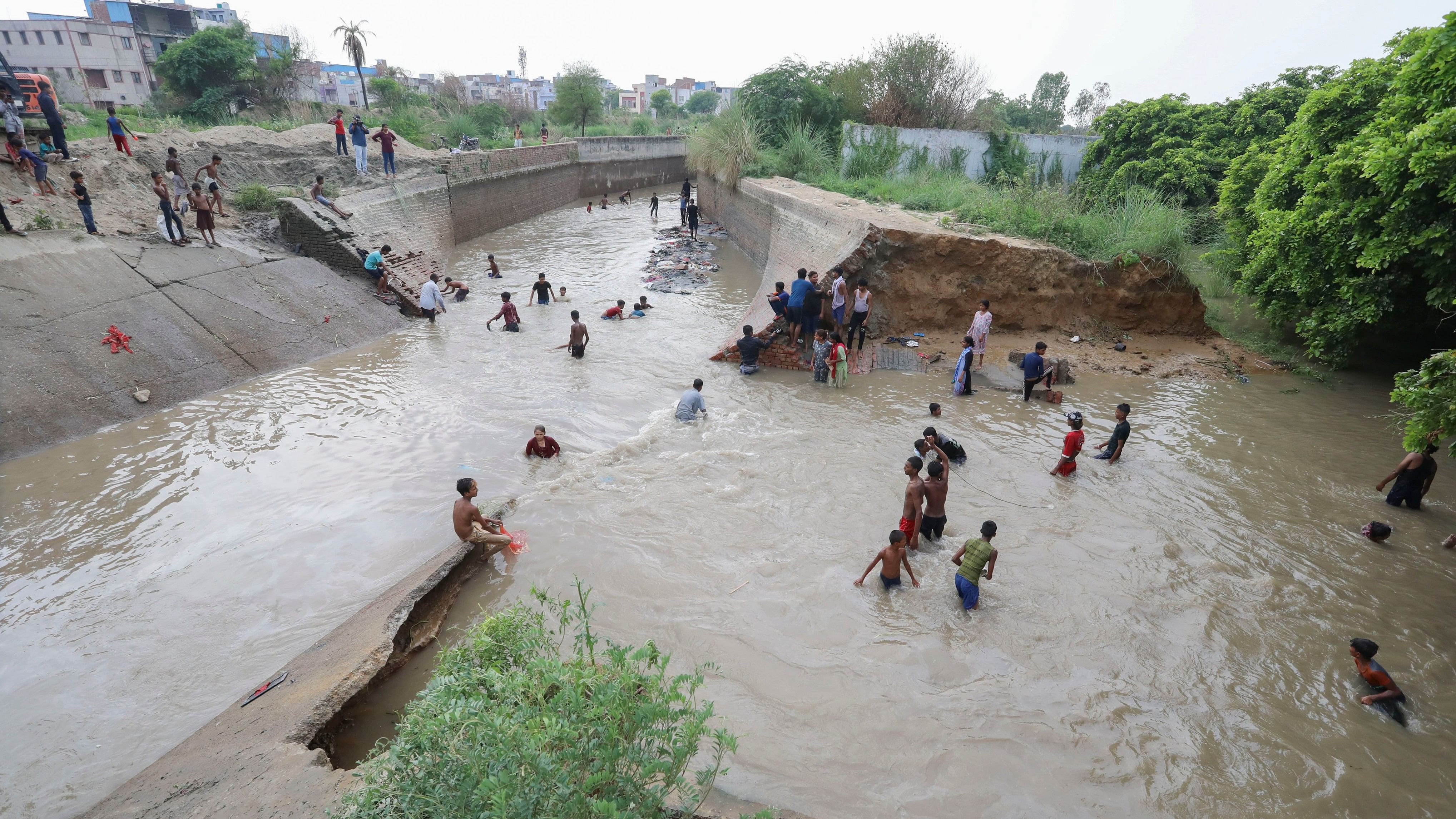 <div class="paragraphs"><p>People make their way through a flooded area after a breach in Munak canal that supplies water from Haryana to Delhi.</p></div>