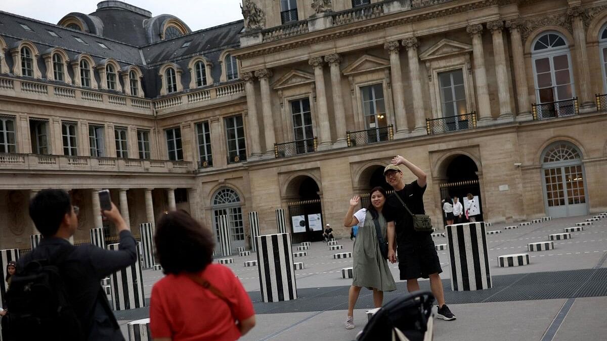 <div class="paragraphs"><p>Tourists pose for a picture in the courtyard of the Palais Royal ahead of the Paris 2024 Olympics in Paris, France.</p></div>