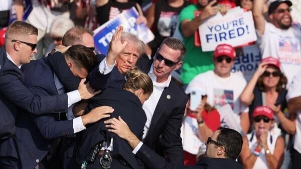 <div class="paragraphs"><p>Republican presidential candidate and former US President Donald Trump gestures with a bloodied face while he is assisted by US Secret Service personnel after he was shot in the right ear during a campaign rally at the Butler Farm Show in Butler, Pennsylvania.</p></div>