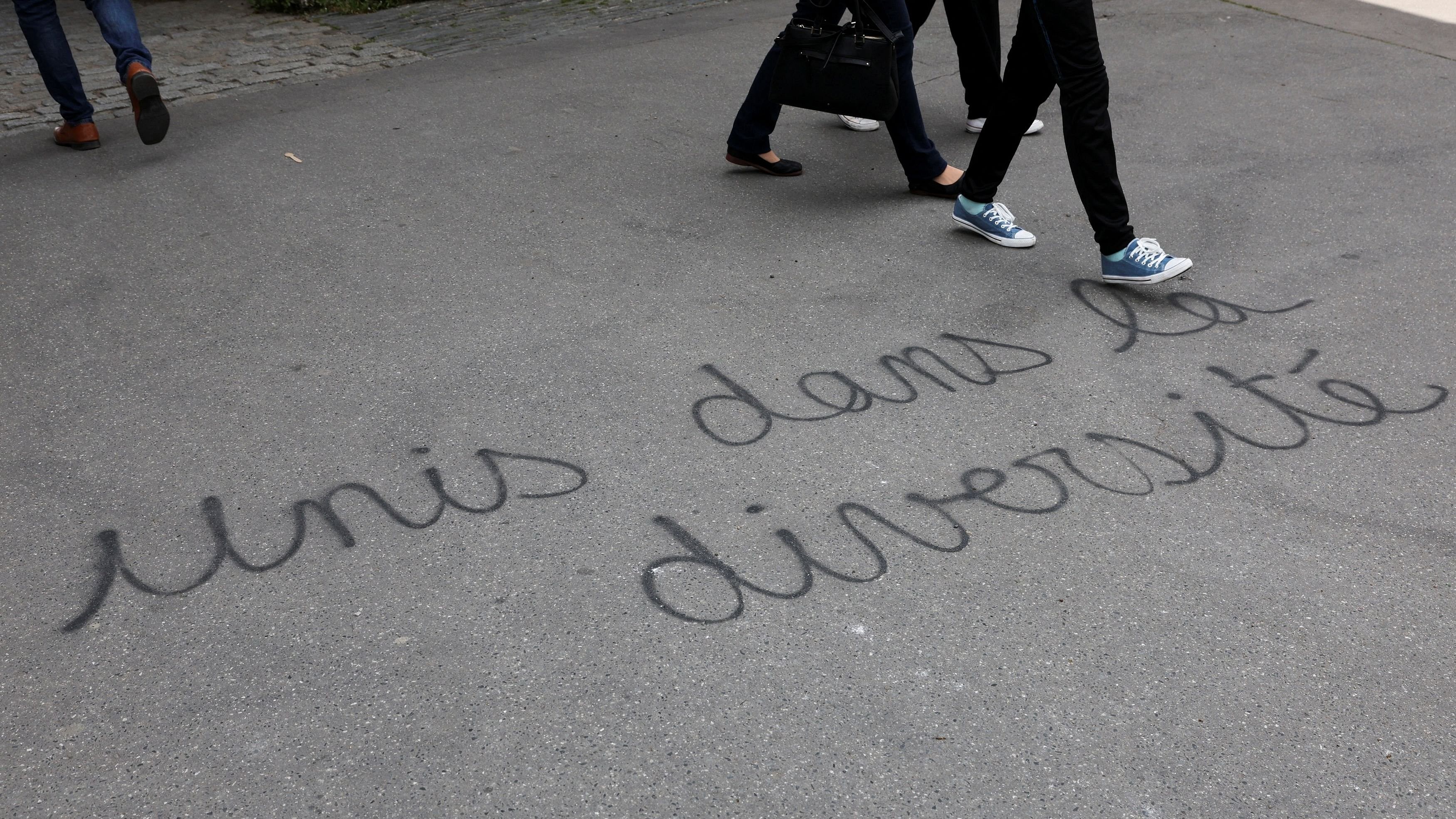<div class="paragraphs"><p>People walk past a graffiti reading 'United in diversity'</p></div>