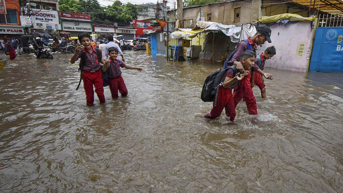 <div class="paragraphs"><p>School children walk through a waterlogged road after rains, in Patna, Friday, July 5, 2024.</p></div>