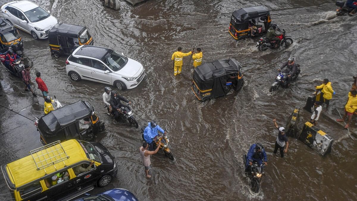 <div class="paragraphs"><p>Commuters wade through a waterlogged street following rains in Maharashtra.</p></div>