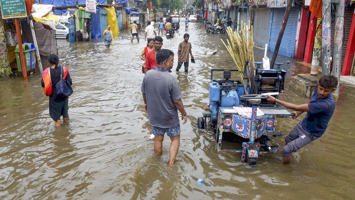 <div class="paragraphs"><p>Commuters wade through a waterlogged road, following rains in Patna, Bihar, Sunday on July 7, 2024.</p></div>