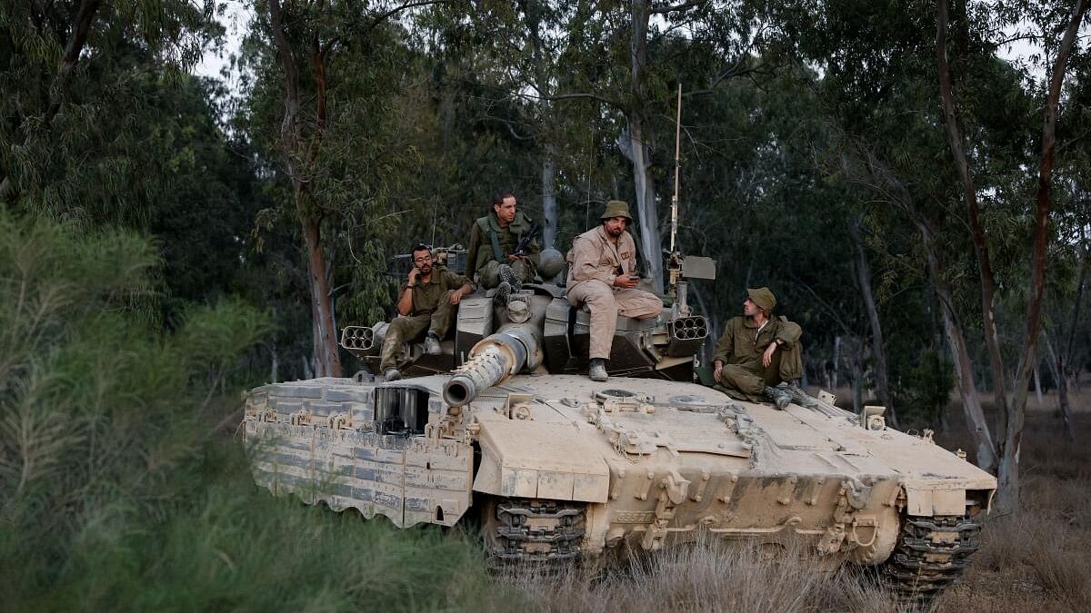 <div class="paragraphs"><p>Israeli soldiers rest on top of a tank near the Israel-Gaza border, amid the Israel-Hamas conflict, in Israel.</p></div>