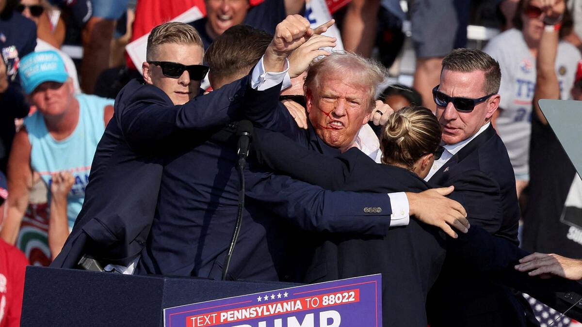 <div class="paragraphs"><p>Republican presidential candidate and former US President Donald Trump gestures with a bloodied face while he is assisted by US Secret Service personnel after he was shot in the right ear during a campaign rally at the Butler Farm Show in Butler, Pennsylvania, US, July 13, 2024.</p></div>