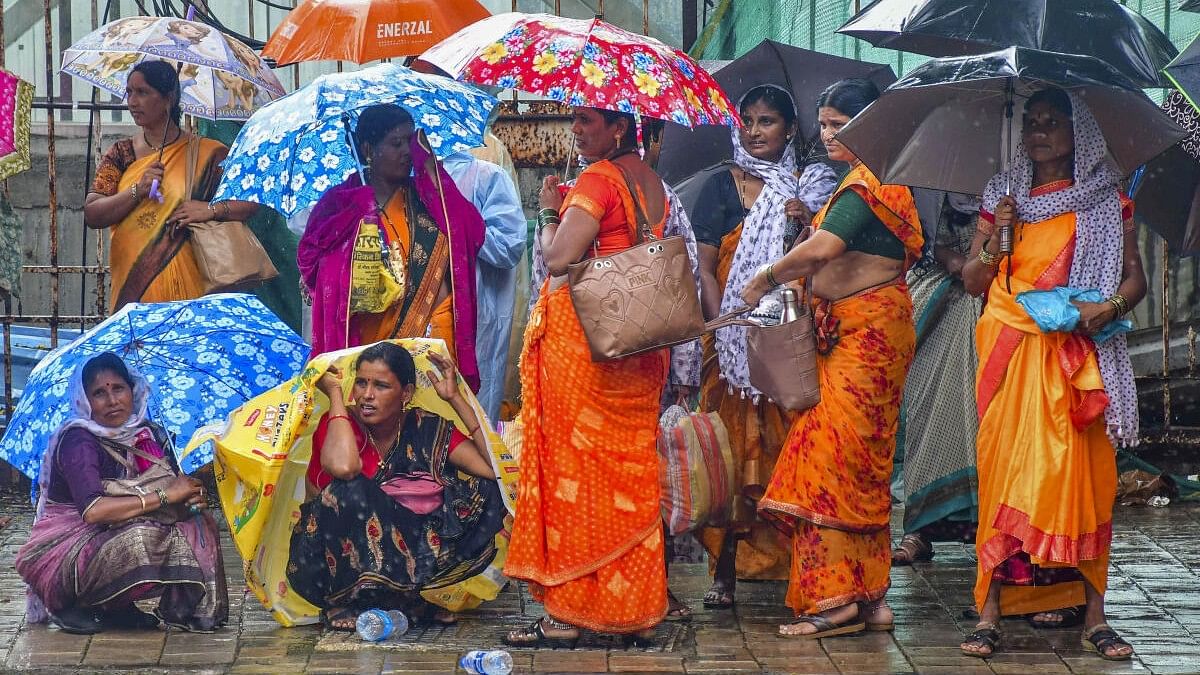 <div class="paragraphs"><p>Women take cover under umbrellas during rain, near Chhatrapati Shivaji Terminus (CST) in Mumbai.</p></div>