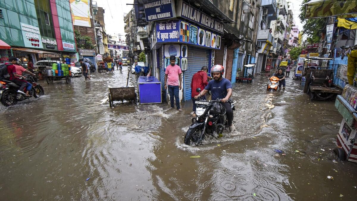 <div class="paragraphs"><p>Commuters wade through a waterlogged road after rains, in Patna.</p></div>