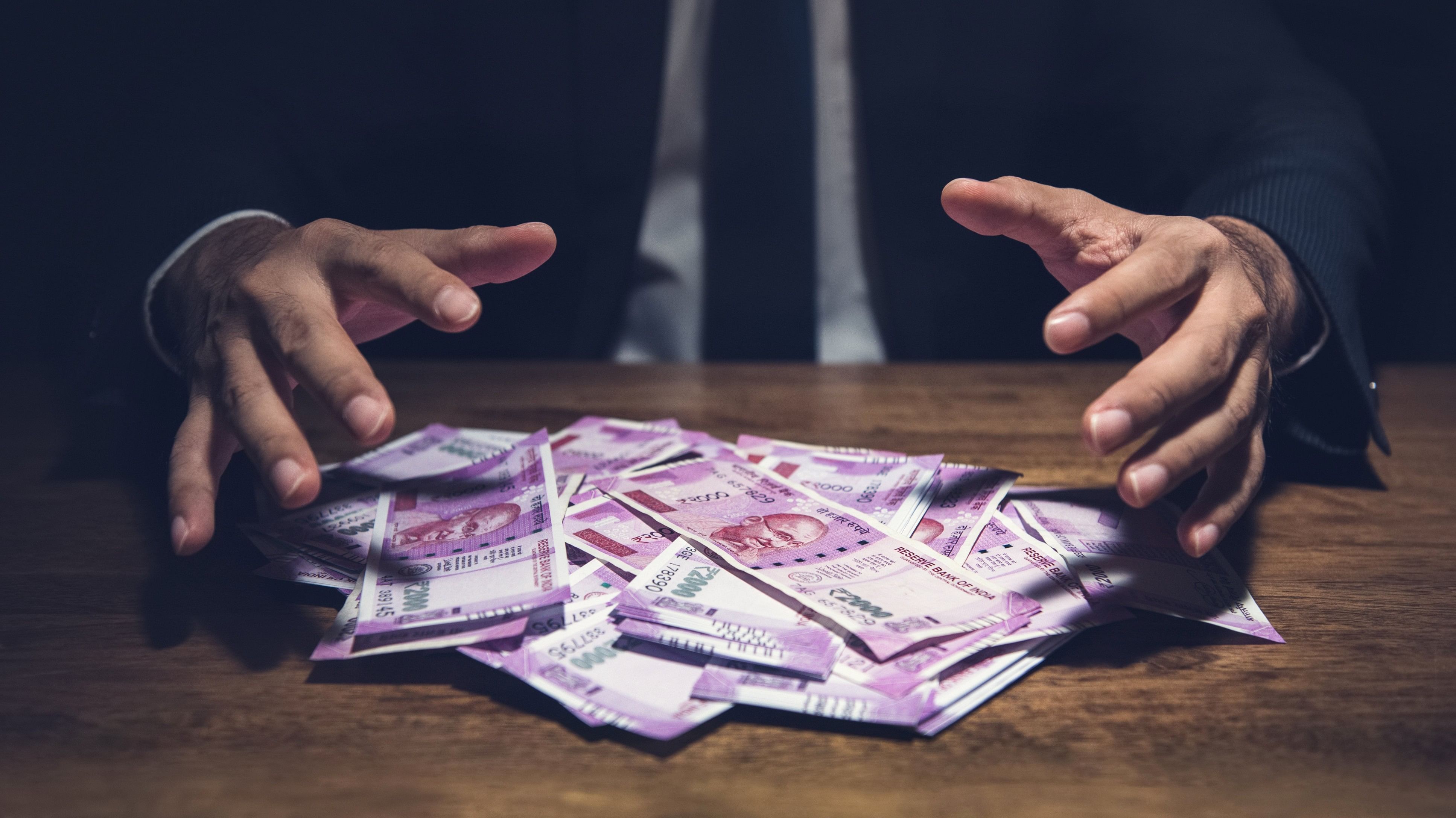 Businessman taking pile of money, Indian Rupee banknotes, on his desk in a dark office - corruption concept
currency