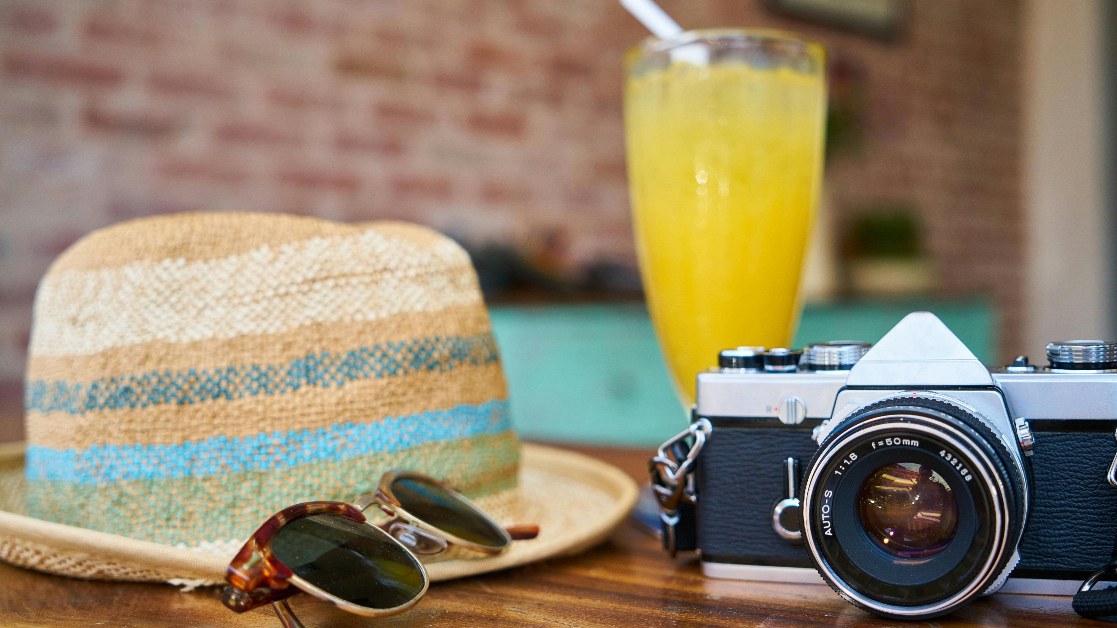 <div class="paragraphs"><p>DSLR Camera beside Hat and Sunglasses.</p></div>