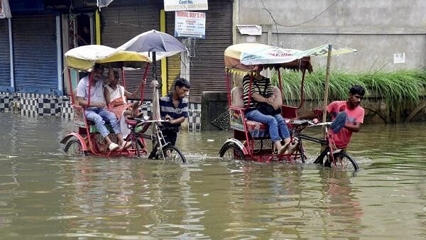 <div class="paragraphs"><p>Rickshaw pullers wade through a flooded street after rainfall, in Guwahati, Assam.</p></div>