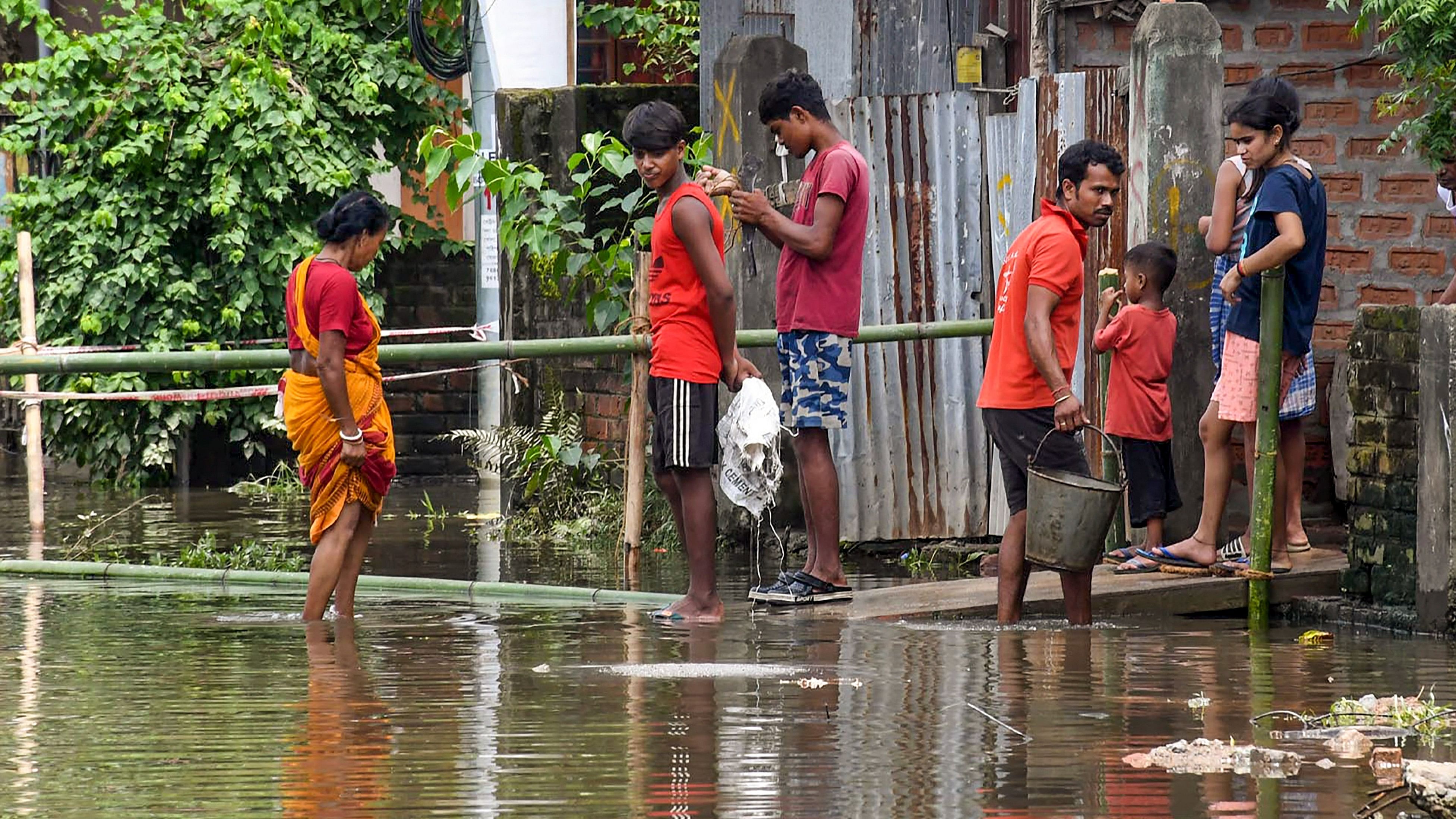 <div class="paragraphs"><p>People wade through a waterlogged area of Rukmoni Gaon, in Guwahati, Saturday.</p></div>