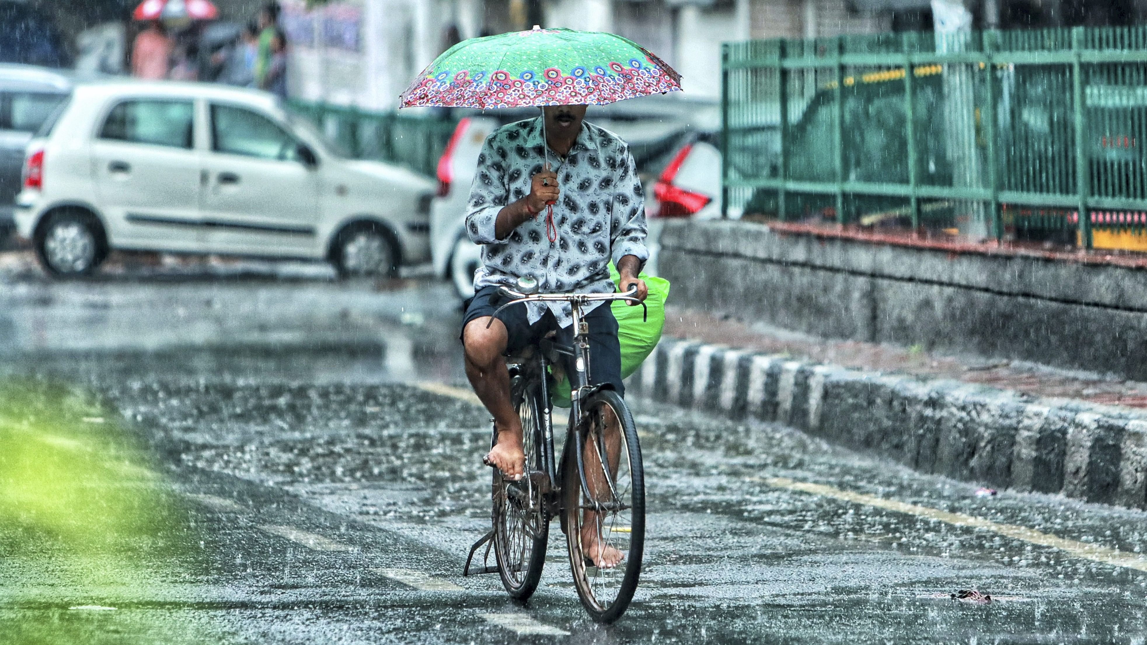 <div class="paragraphs"><p>A man rides a bicycle while holding an umbrella during rain, at Jangpura area, in New Delhi, Thursday, July 25, 2024.</p></div>