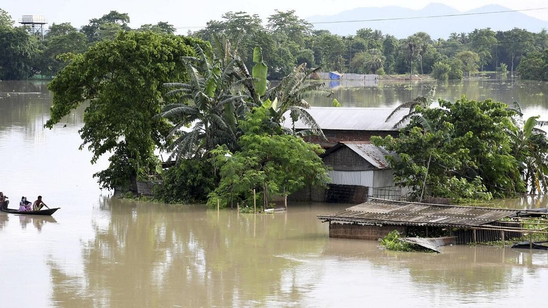 <div class="paragraphs"><p>People on a boat move past houses submerged in the floodwater, in Morigaon district in Assam.&nbsp;</p></div>