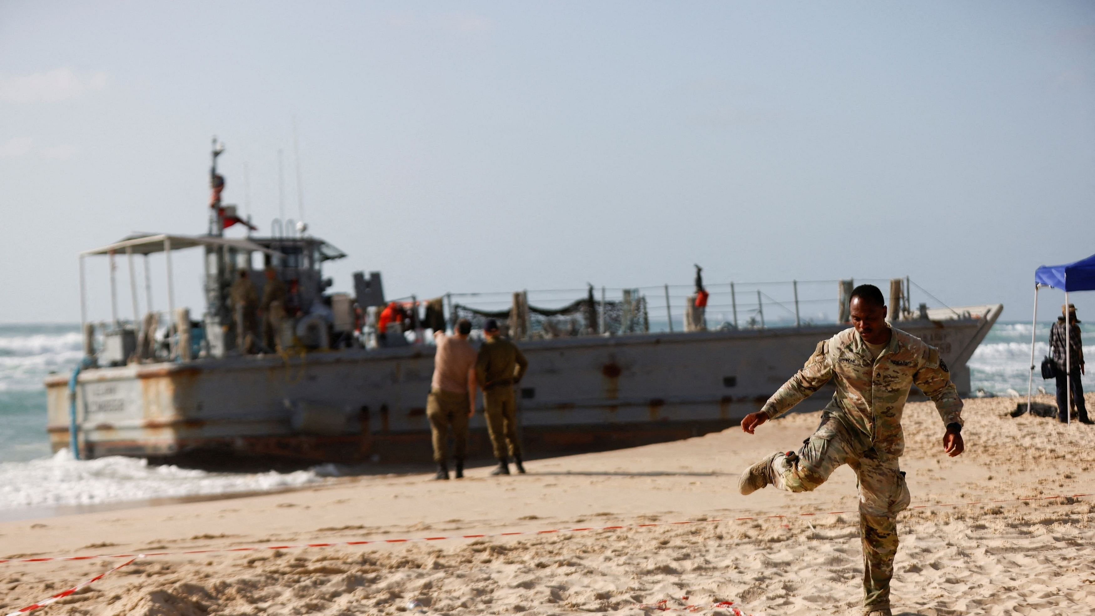 <div class="paragraphs"><p>A US soldier leaves a cordoned-off area as other troops work on a beached vessel, used for delivering aid to Palestinians via a new US-built pier in Gaza, after it got stuck trying to help another vessel behind it, on the Mediterranean coast in Ashdod, Israel May 25, 2024. </p></div>