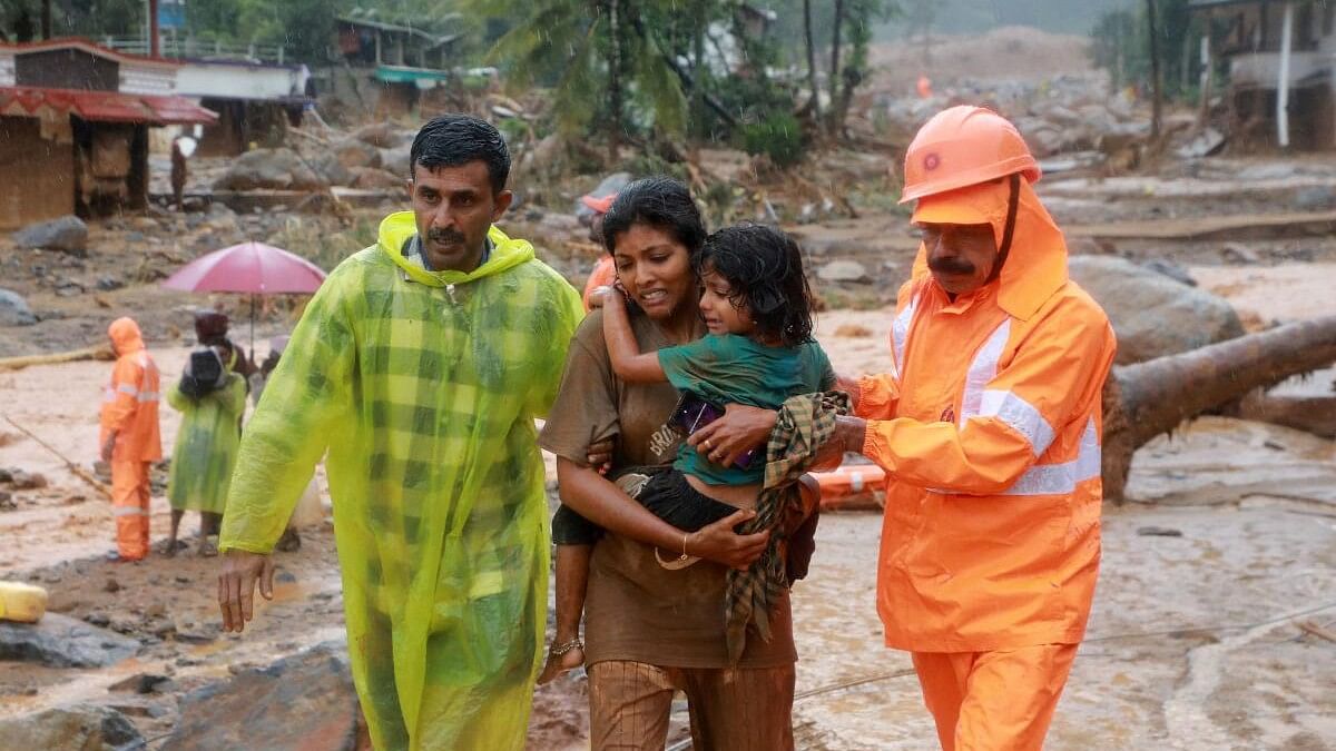 <div class="paragraphs"><p>Rescuers help residents to move to a safer place, at a landslide site after multiple landslides in the hills, in Wayanad.</p></div>