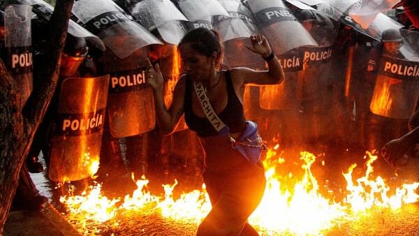 <div class="paragraphs"><p>A demonstrator reacts when Molotov cocktails hit the ground in front of security forces during protests against election results after Venezuela's President Nicolas Maduro and his opposition rival Edmundo Gonzalez claimed victory in Sunday's presidential election, in Puerto La Cruz, Venezuela July 29, 2024.</p></div>