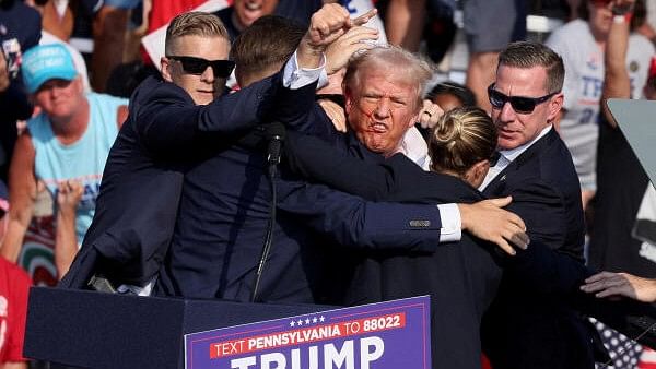 <div class="paragraphs"><p>Republican presidential candidate and former US President Donald Trump gestures with a bloodied face while he is assisted by US Secret Service personnel after he was shot in the right ear during a campaign rally at the Butler Farm Show in Butler, Pennsylvania, US.</p></div>