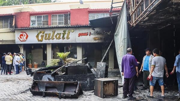 <div class="paragraphs"><p>People stand outside Gulati Restaurant where a fire broke out, in New Delhi, early Wednesday, July 17, 2024.</p></div>