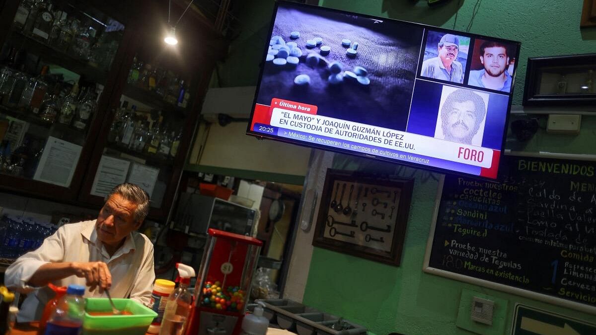 <div class="paragraphs"><p>A barman stands next to a TV showing the news of the arrest of Mexican drug lord Ismael 'El Mayo' Zambada and the son of his former partner, Joaquin 'El Chapo' Guzman at a private airport in El Paso, Texas, at a cantina in Mexico City, Mexico.</p></div>