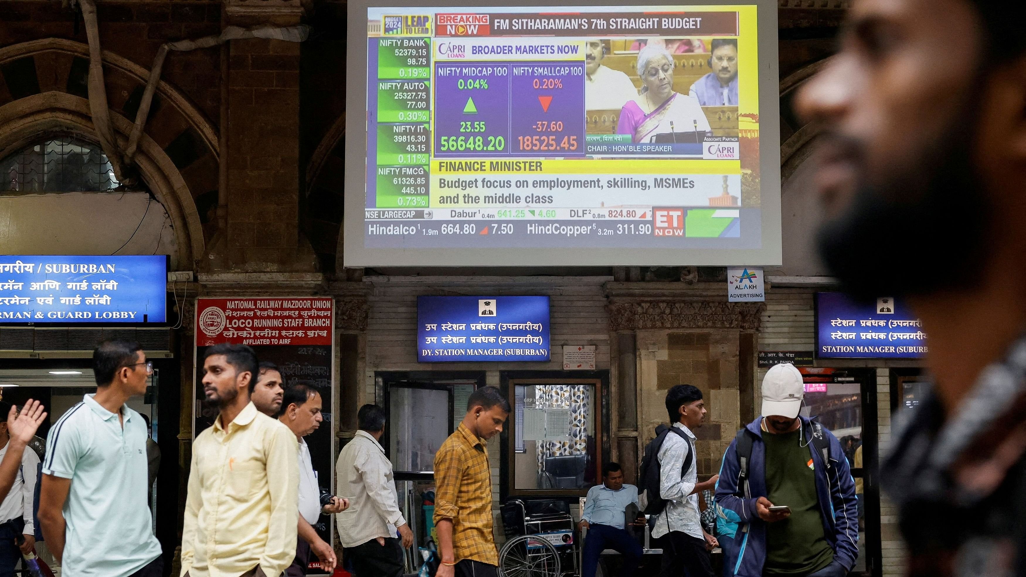 <div class="paragraphs"><p> People walk past a screen displaying Finance Minister Nirmala Sitharaman's Budget speech at a railway station in Mumbai, July 23, 2024. </p></div>