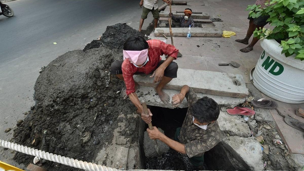 <div class="paragraphs"><p>Workers clean a sewer manually in Delhi.</p></div>