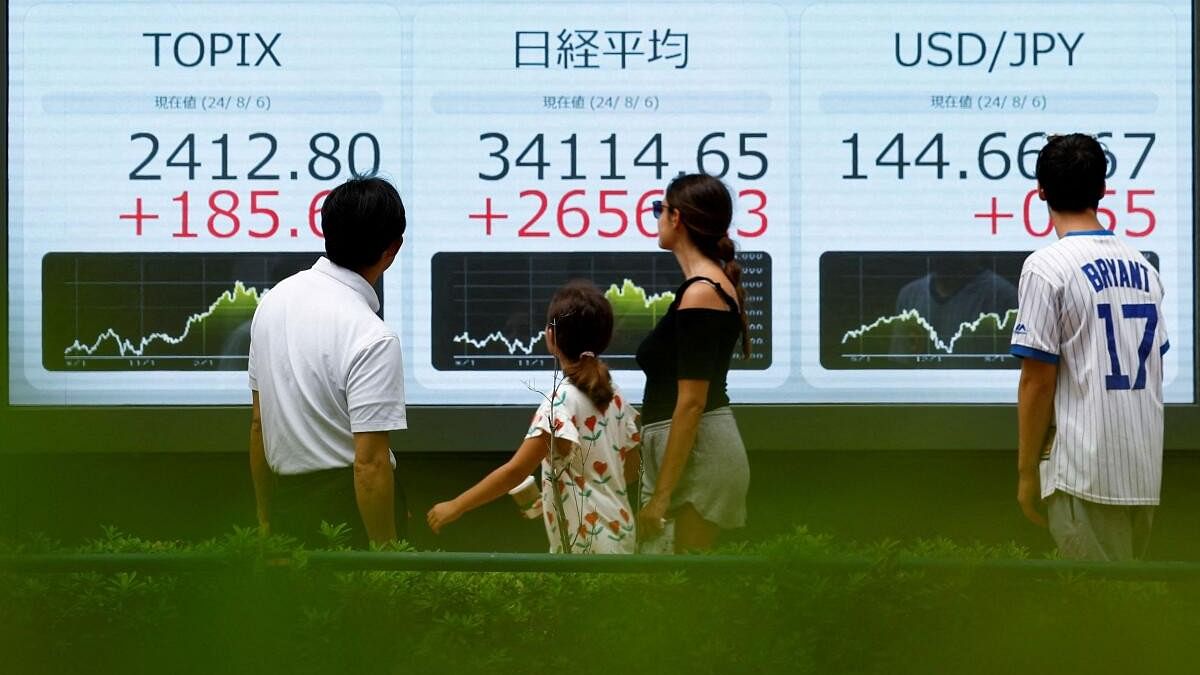 <div class="paragraphs"><p>Passersby look at an electronic board displaying Topix, Japan's Nikkei share averages, and Japanese yen exchange rate against the US dollar.</p></div>