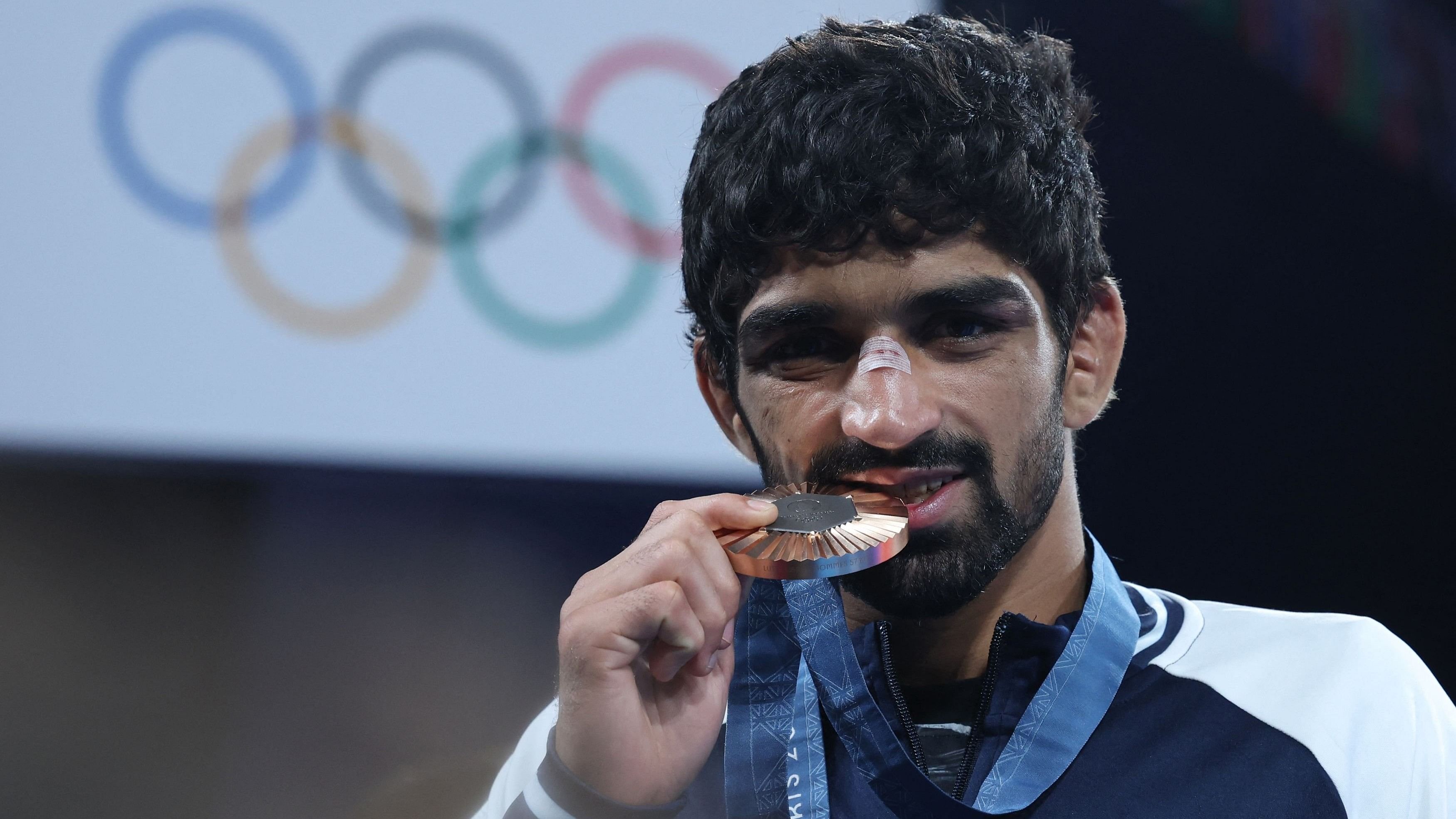 <div class="paragraphs"><p>Bronze medallist Aman Sehrawat of India bites his medal.</p></div>