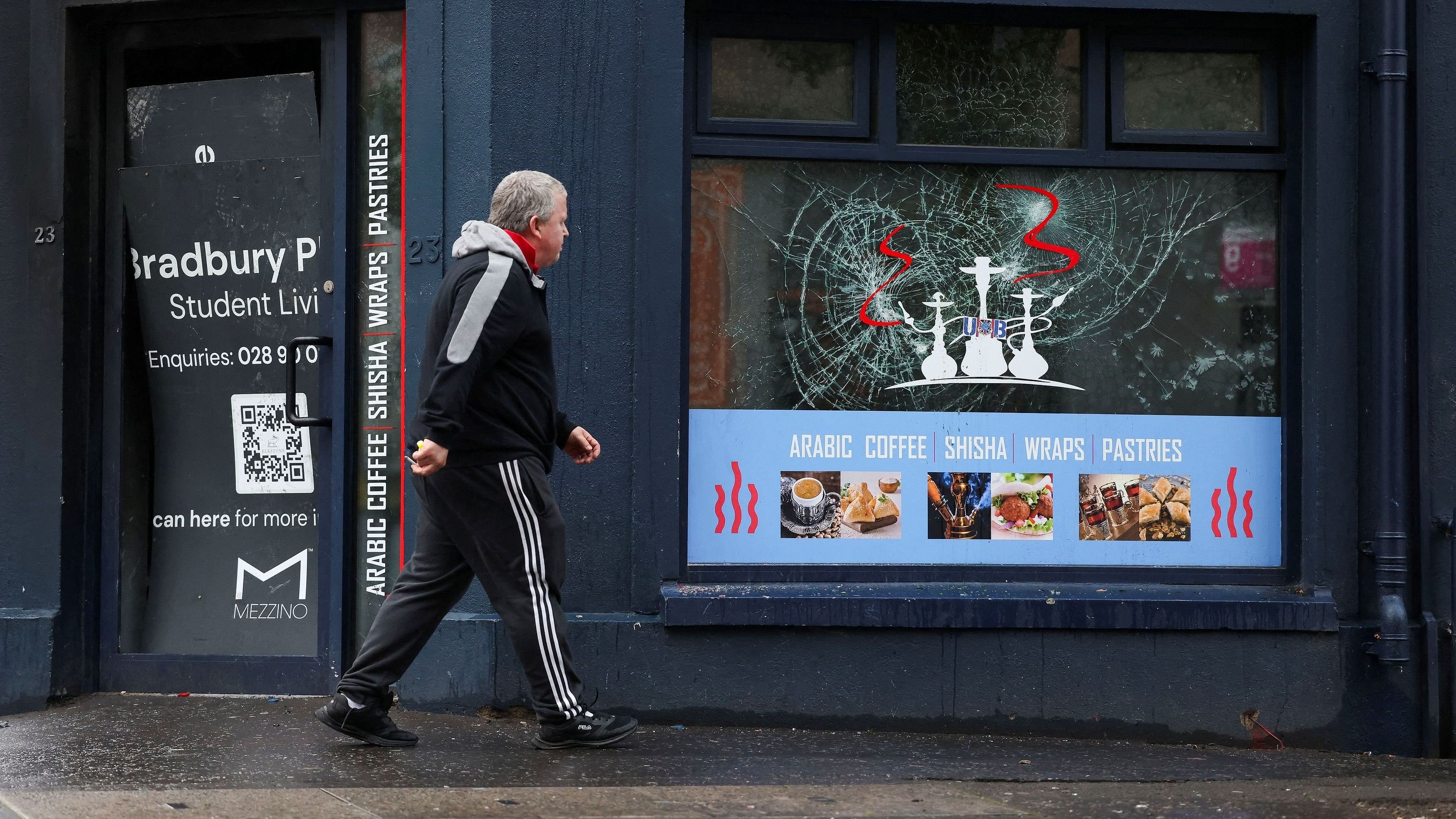 A man walks past a cafe that was set on fire during anti-immigration protests on Saturday in Belfast, Northern Ireland, August 8, 2024. REUTERS/Hollie Adams