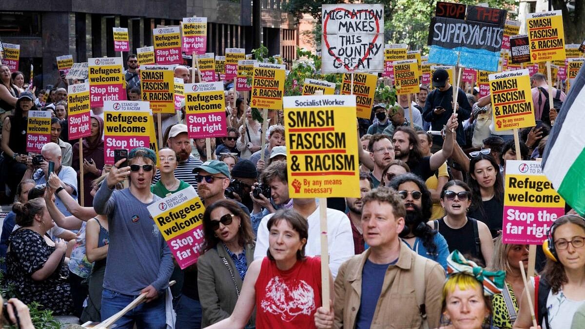 <div class="paragraphs"><p>People hold signs at a protest against racism outside Reform UK's headquarters in Westminster, in London, Britain.</p></div>