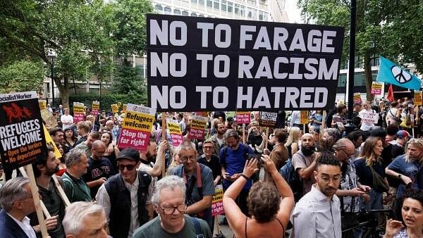 <div class="paragraphs"><p>People hold signs at a protest against racism outside Reform UK's headquarters in Westminster, in London, Britain.</p></div>