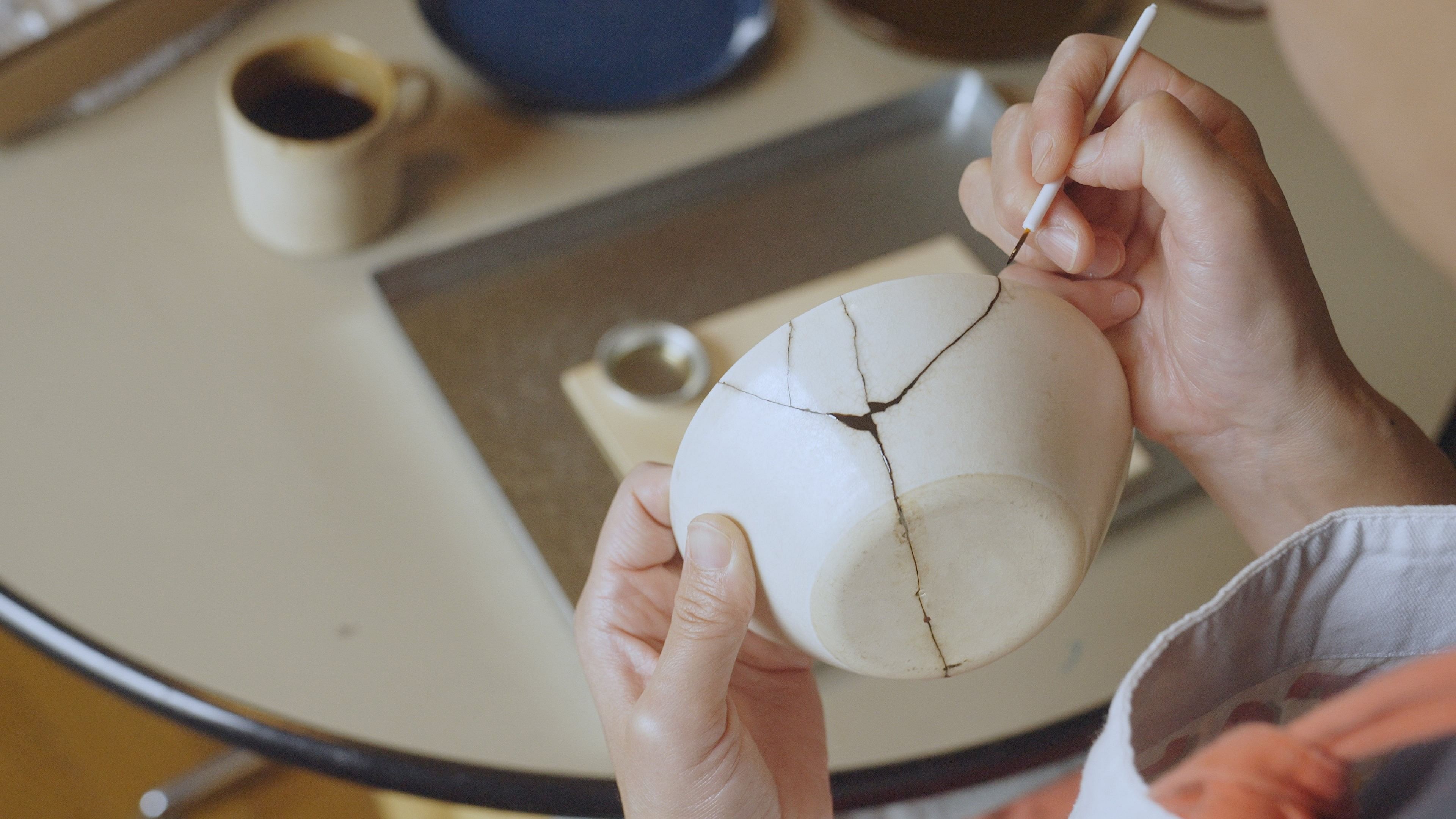 <div class="paragraphs"><p>Woman repairing broken pottery at home using the art of Kintsugi.</p></div>