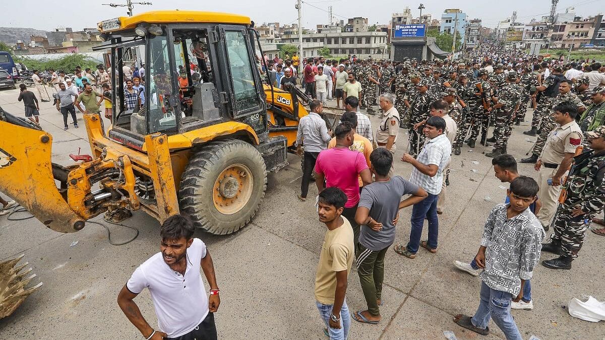 <div class="paragraphs"><p>Residents gather near a bulldozer as they try to stop a demolition drive by the MCD in Bhalswa area of New Delhi on August 13.&nbsp;</p></div>