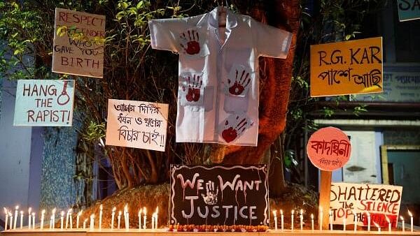 <div class="paragraphs"><p>Candles burn, as posters hang on a tree in protest against alleged rape and murder of a trainee doctor, inside the premises of Dr. R. Ahmed Dental College and Hospital in Kolkata.&nbsp;</p></div>