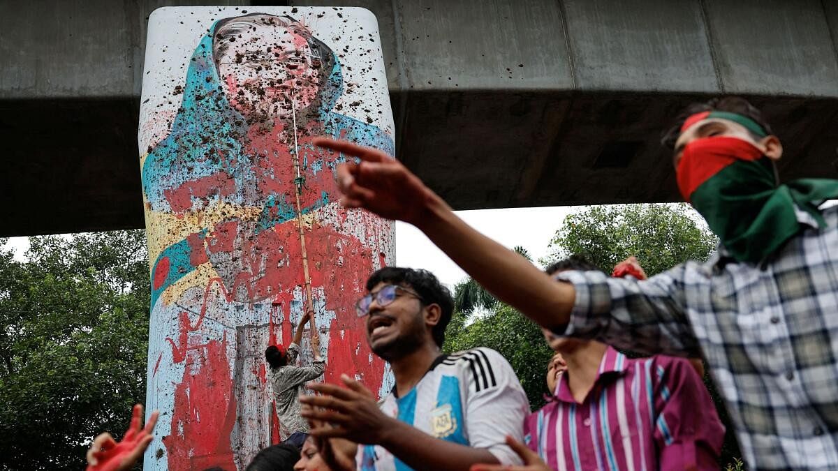 <div class="paragraphs"><p>Protesters shout slogans as they vandalise a mural of  Sheikh Hasina in Dhaka.</p></div>