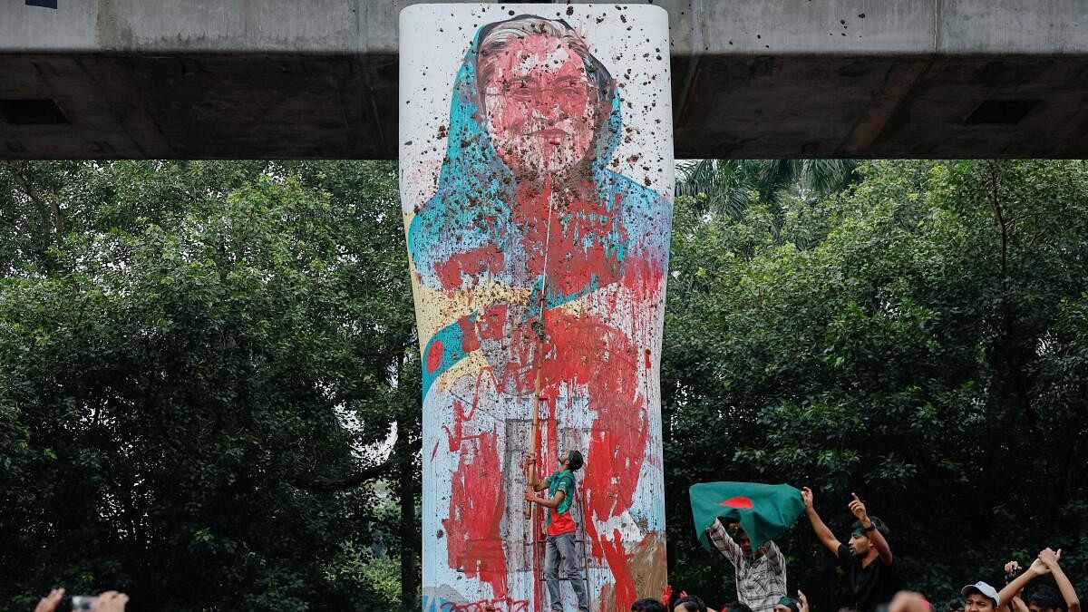 <div class="paragraphs"><p>Protesters shout slogans as they vandalise a mural of Bangladeshi Prime Minister Sheikh Hasina with paint and mud.</p></div>