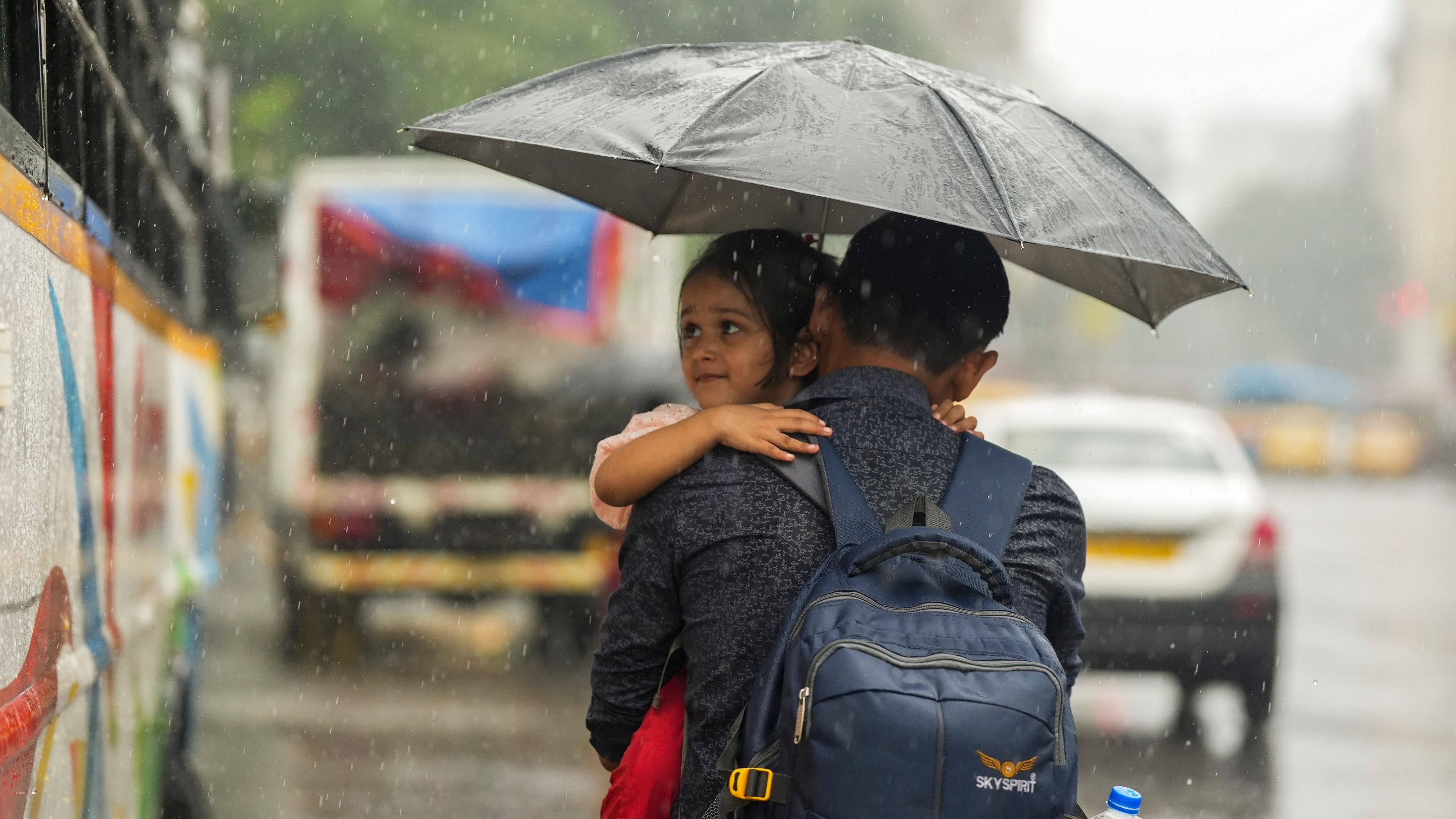 <div class="paragraphs"><p> A pedestrian carrying his daughter amid monsoon rain, in Kolkata.</p></div>