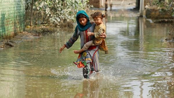 <div class="paragraphs"><p>File Photo of a girl carrying her sibling as she walks through stranded flood water, following rains and floods during the monsoon season in Pakistan.&nbsp;</p></div>