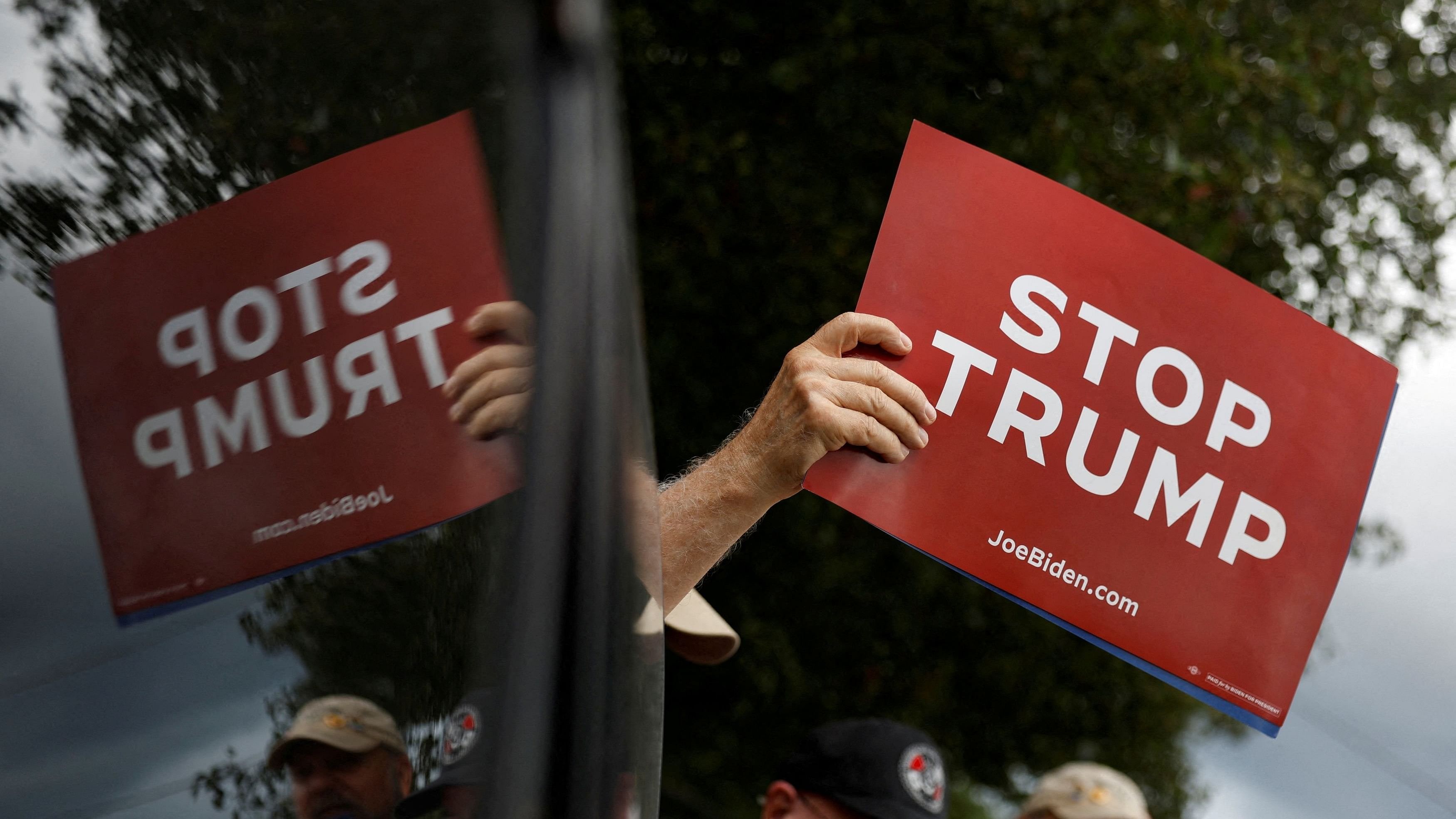 <div class="paragraphs"><p>A supporter of the Democratic presidential candidate Kamala Harris holds a banner as he attends a  protest outside a factory where the Republican presidential candidate and former US President Donald Trump will deliver economic remarks, in York, Pennsylvania, US.</p></div>