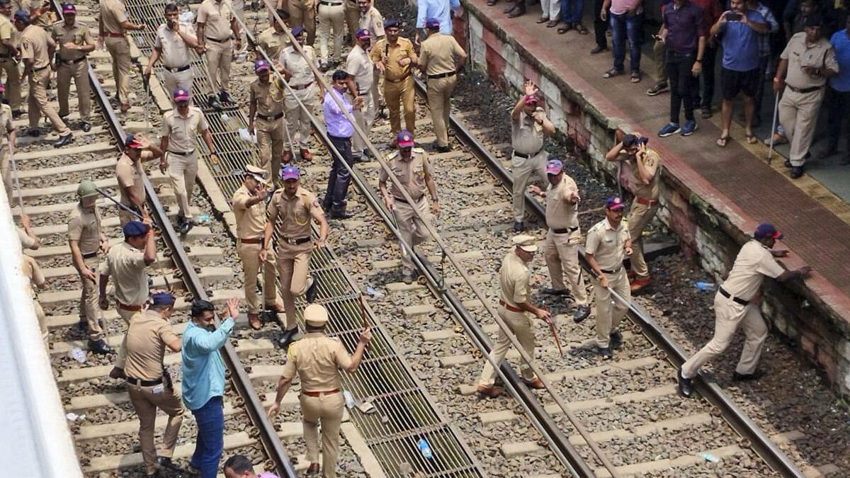 <div class="paragraphs"><p>Police personnel try to disperse people blocking railway tracks in protest against the alleged sexual abuse of two girls at a school at Badlapur railway station.</p></div>