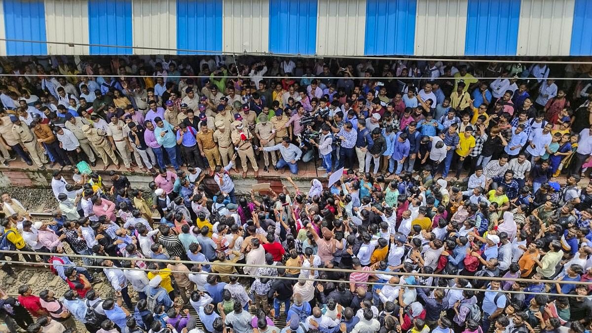 <div class="paragraphs"><p>Police personnel speak with people blocking railway tracks in protest against the alleged sexual abuse of two girls at a school, at Badlapur railway station, in Thane district, Tuesday, Aug. 20, 2024.</p></div>