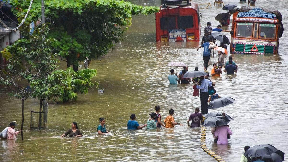 <div class="paragraphs"><p>People wade through a waterlogged street at Parel area, after heavy monsoon rain, in Mumbai.</p></div>