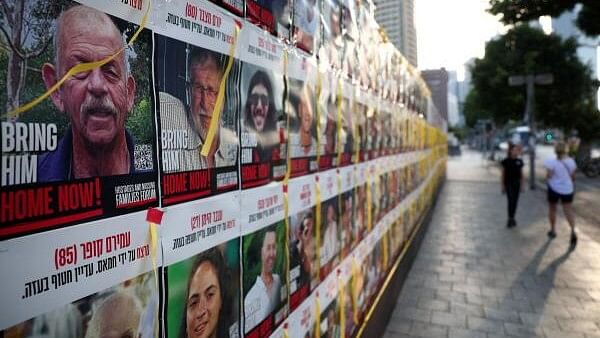 <div class="paragraphs"><p>People walk next to a wall of posters of hostages kidnapped during the deadly October 7 attack on Israel by Hamas, amid the ongoing Israel-Hamas conflict, in Tel Aviv, Israel, August 21, 2024.</p></div>