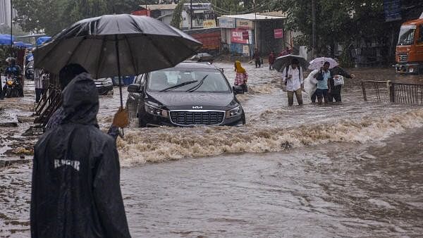 <div class="paragraphs"><p>Commuters wade through a waterlogged road during rains in Gujarat. Representative image</p></div>