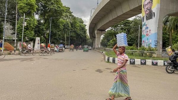 <div class="paragraphs"><p>A man carries a pack of water bottles as he walks past the Raju Memorial opposite the Teacher Student Centre (TSC) of the Dhaka University.</p></div>