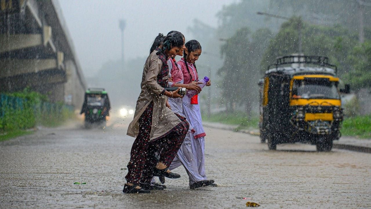 <div class="paragraphs"><p>School students cross the road amid monsoon rains.</p></div>