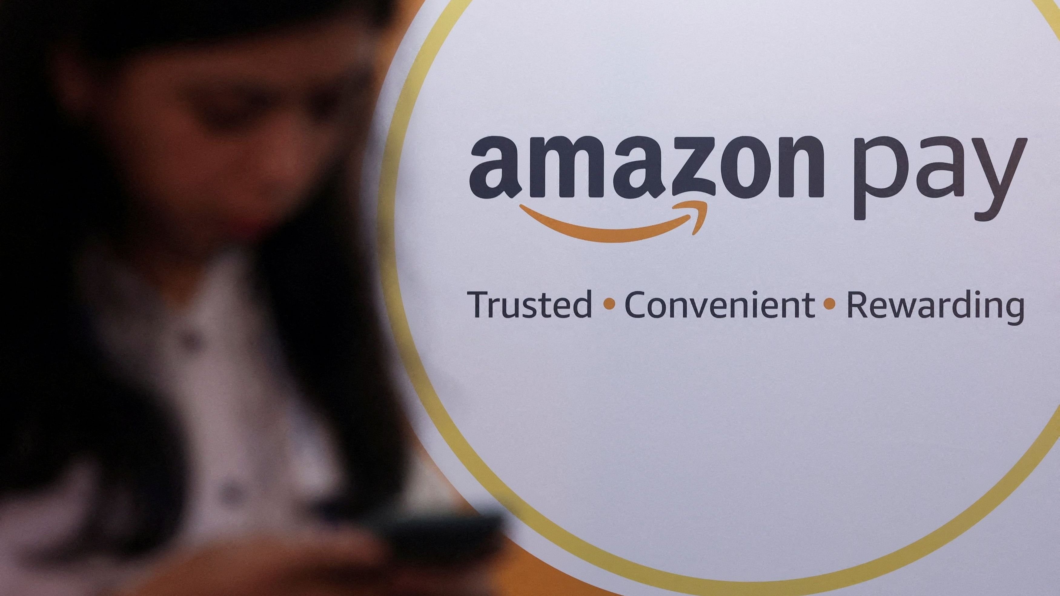 <div class="paragraphs"><p>A woman uses her phone next to a logo of Amazon Pay in Mumbai,&nbsp; September 20, 2022. </p></div>