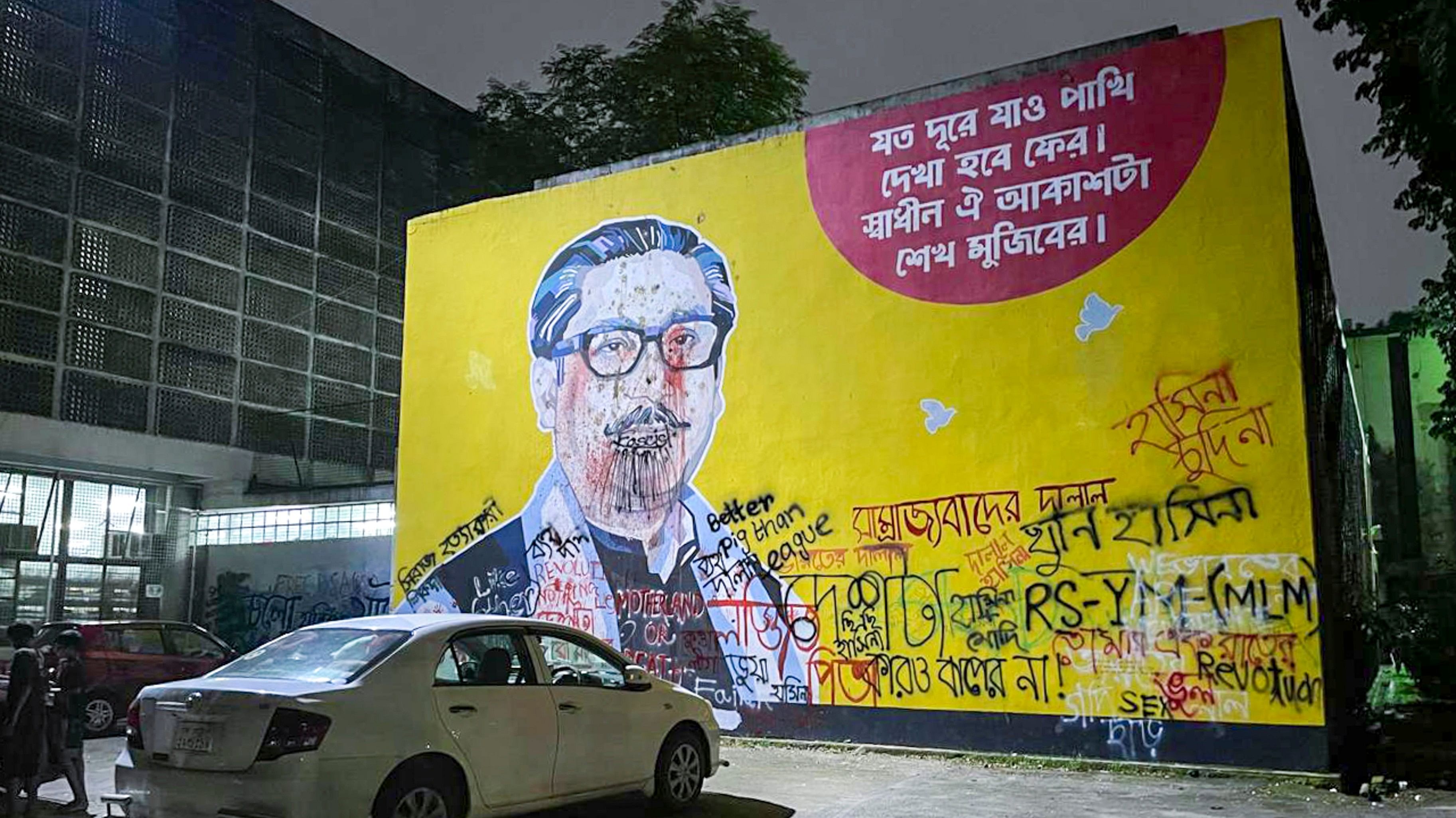 <div class="paragraphs"><p>Dhaka: A mural depicting first president of Bangladesh Sheikh Mujibur Rahman, defaced with graffiti scrawled on a wall in the campus of the Dhaka University, Friday, Aug. 23, 2024.</p></div>