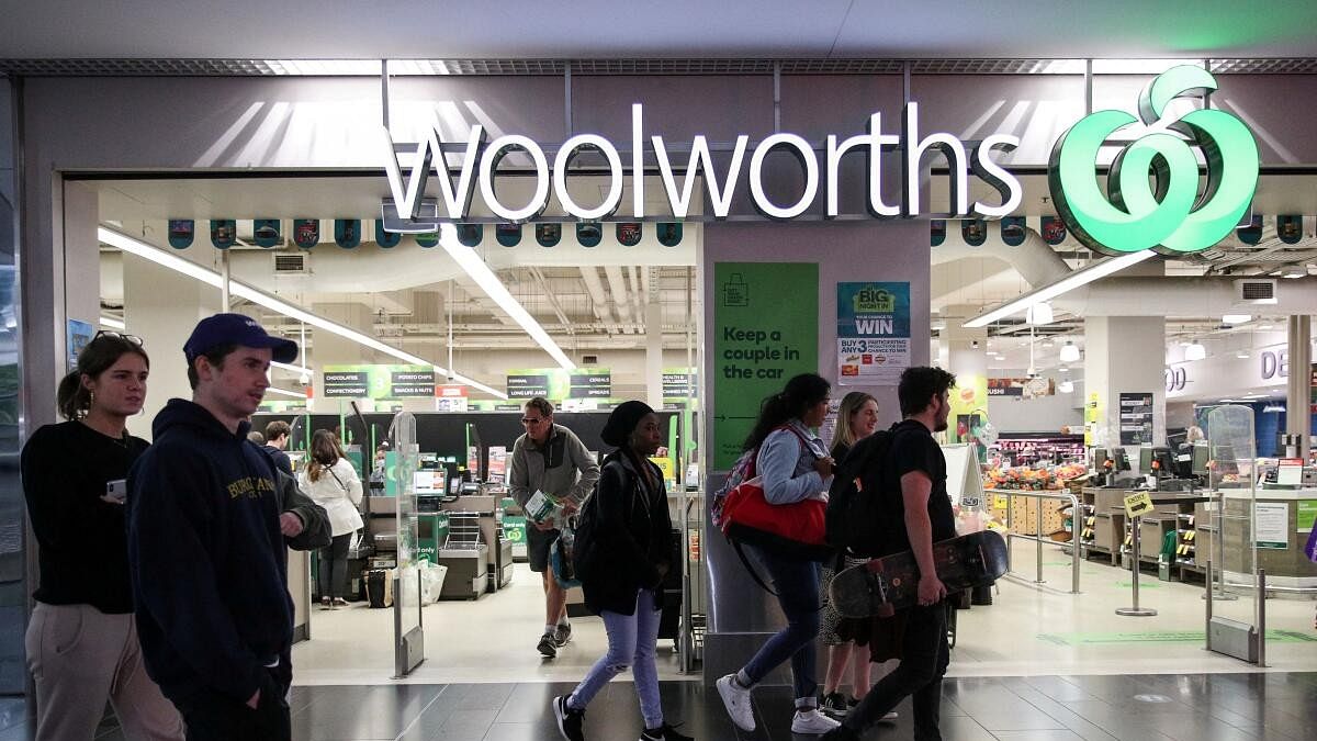 <div class="paragraphs"><p>People walk past a Woolworths supermarket in Sydney</p></div>