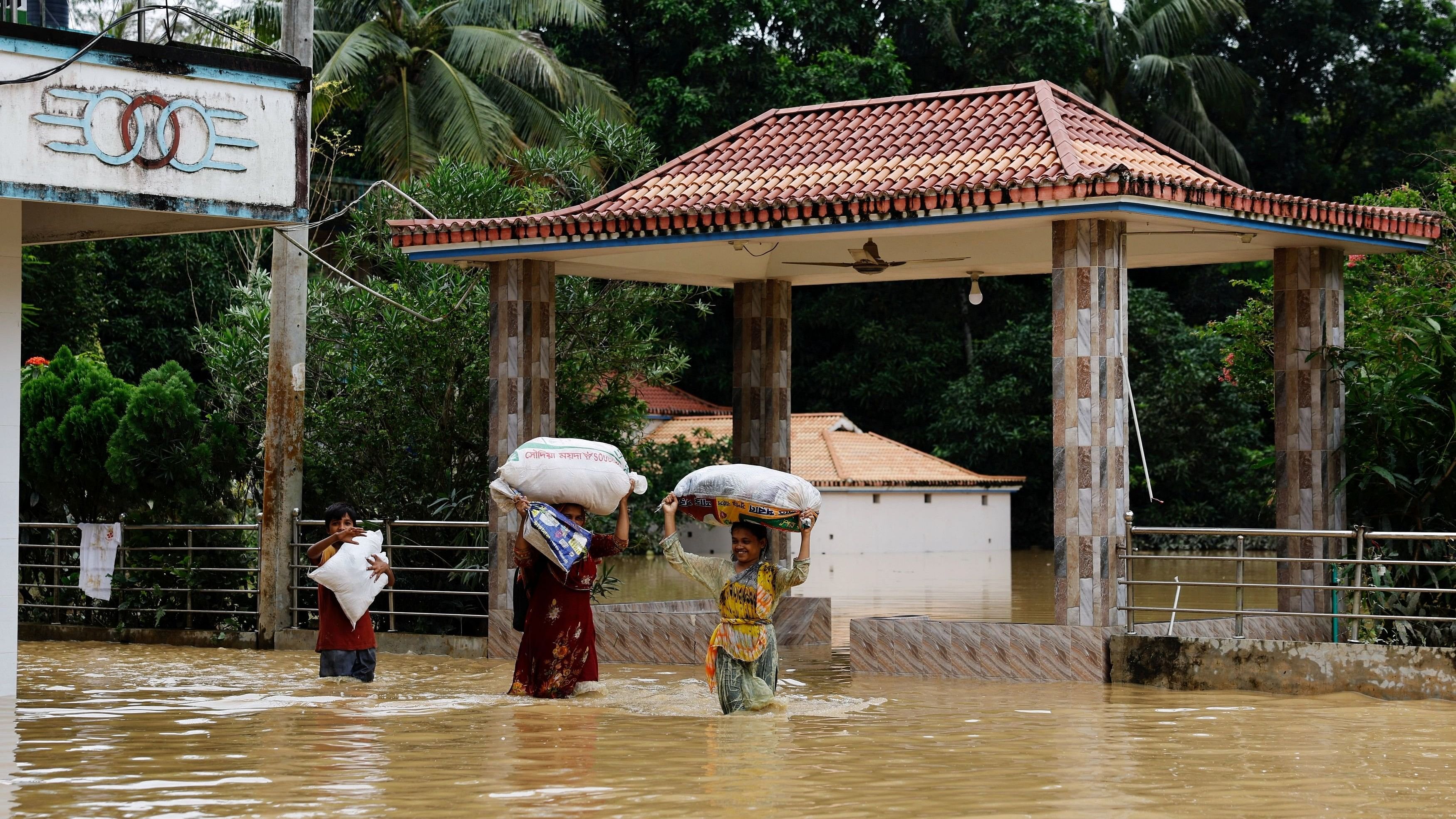 <div class="paragraphs"><p>People carrying sacks, wade through flood water, amid severe flooding in Bangladesh.</p></div>