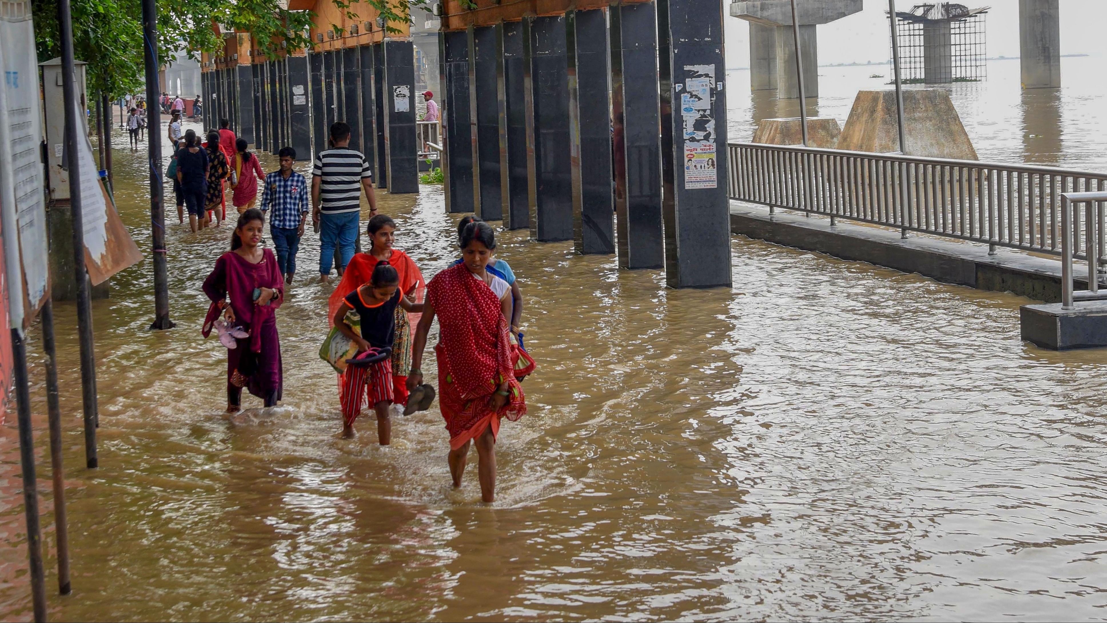 <div class="paragraphs"><p>People wade through a flooded Ganga ghat after rise in water level of the river due to monsoon rains, in Patna.</p></div>